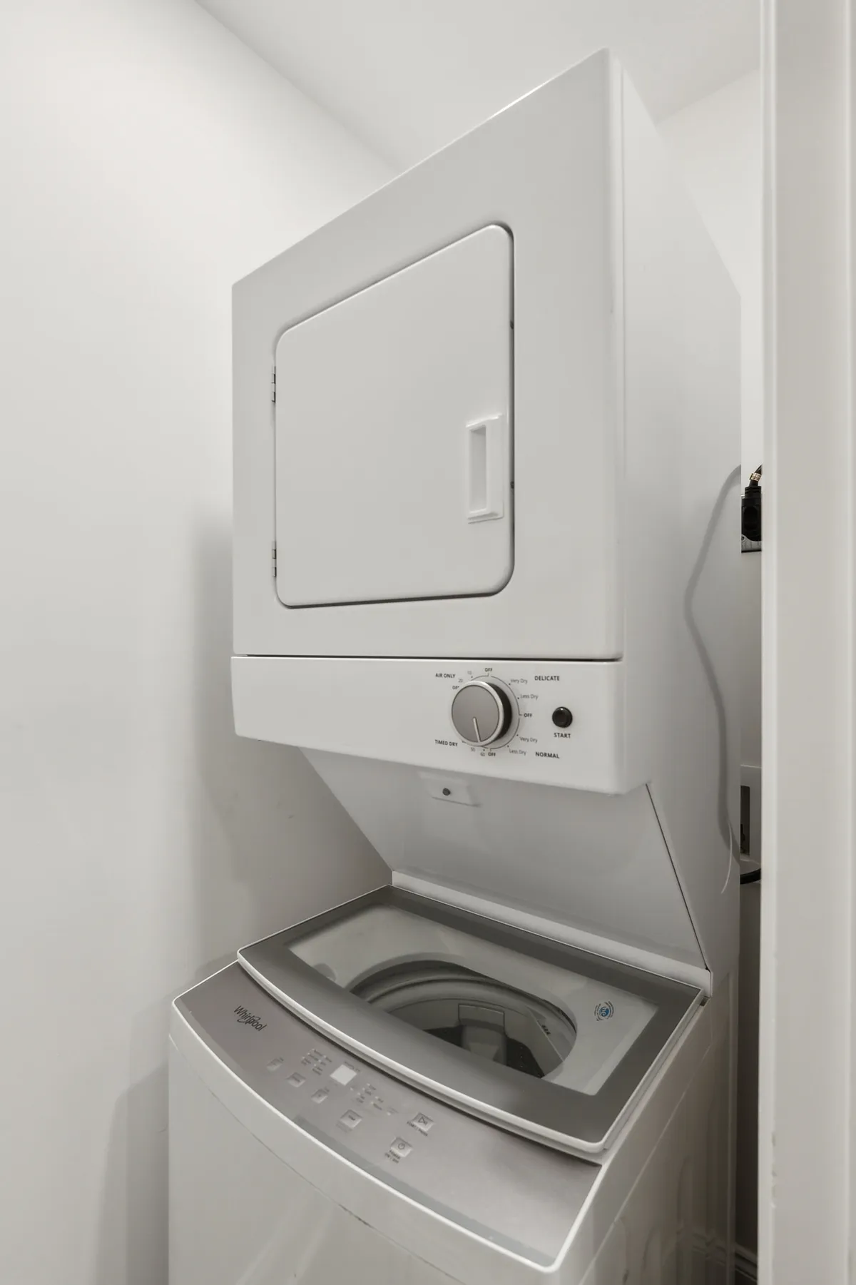 A compact laundry area featuring a stacked washer and dryer unit, with a clear control panel and organized laundry supplies nearby. The scene is bright and practical, emphasizing efficiency and ease of use within the apartment.