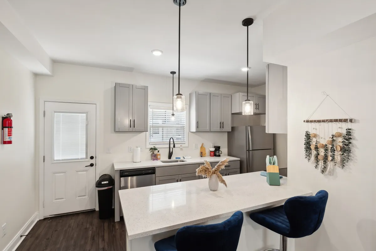 A stylish kitchen featuring a spacious island, modern cabinetry, pendant lights, and a decorative wall hanging. The open layout encourages cooking, socializing, and entertaining, with ample counter space and up-to-date appliances visible.